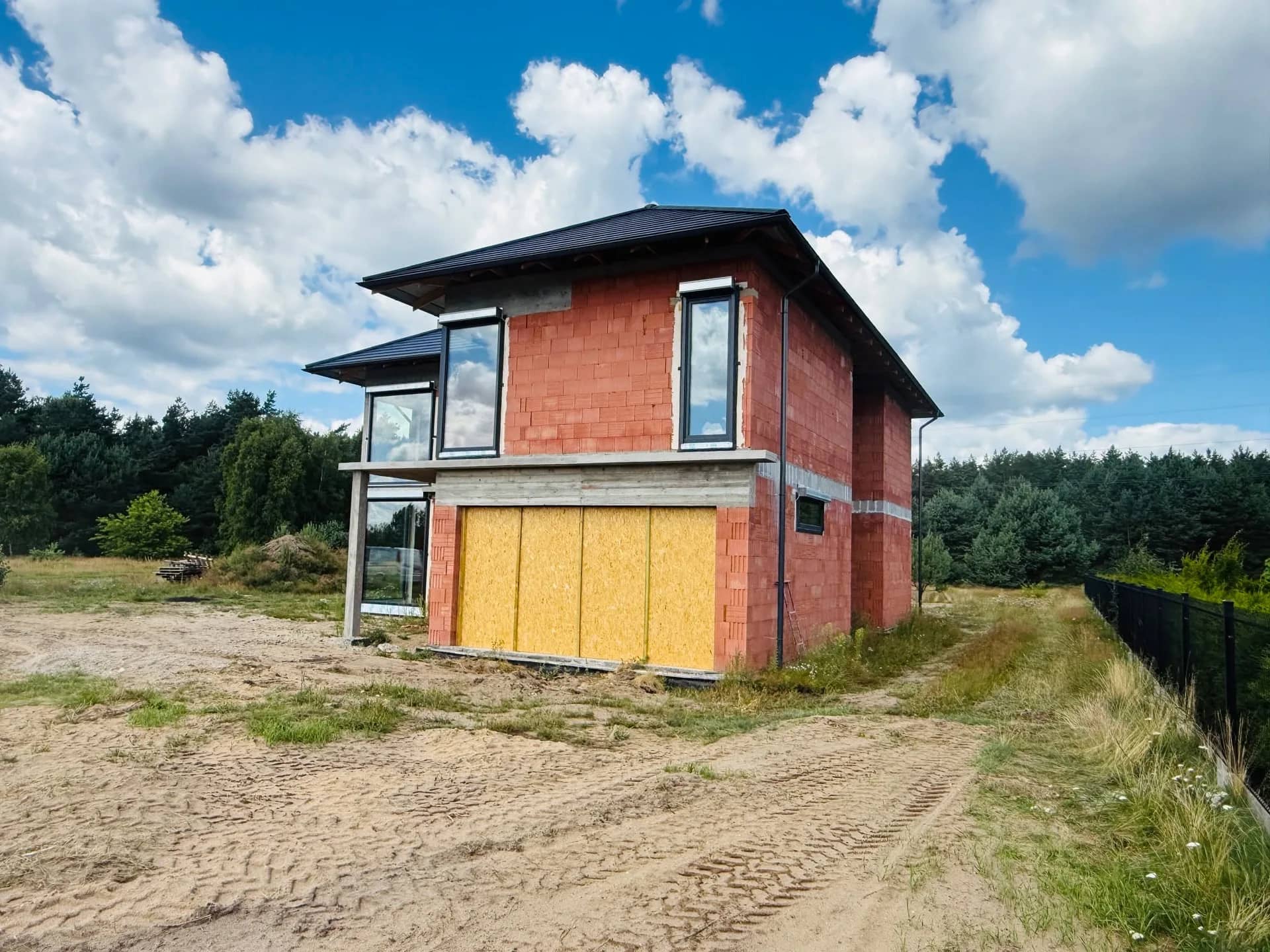 Widok boczny domu w Czarnem — mury z cegły ceramicznej i wykonana konstrukcja dachu
