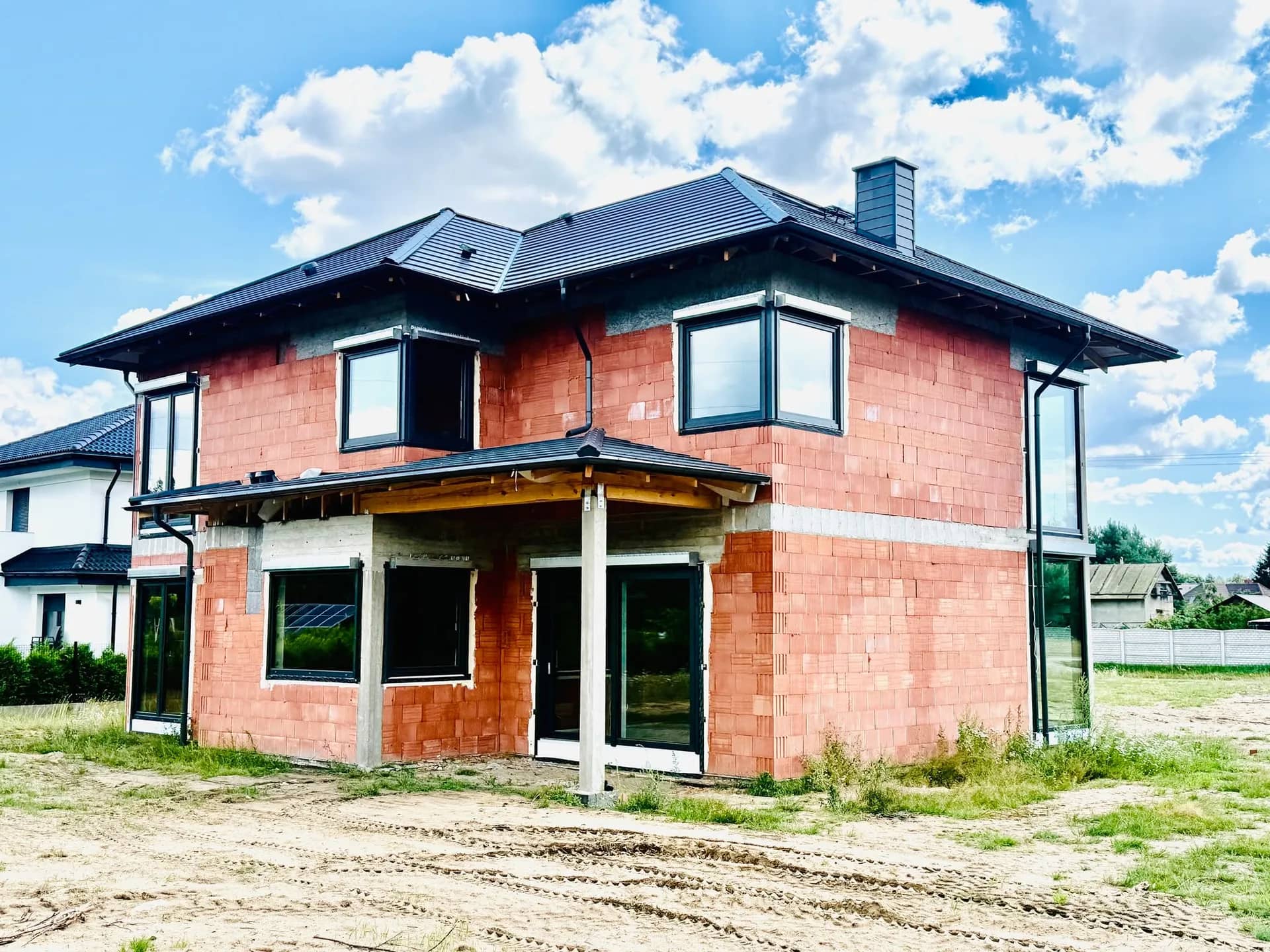 Narożnik domu w Czarnem z zadaszonym wejściem i zamontowaną stolarką okienną VEKA