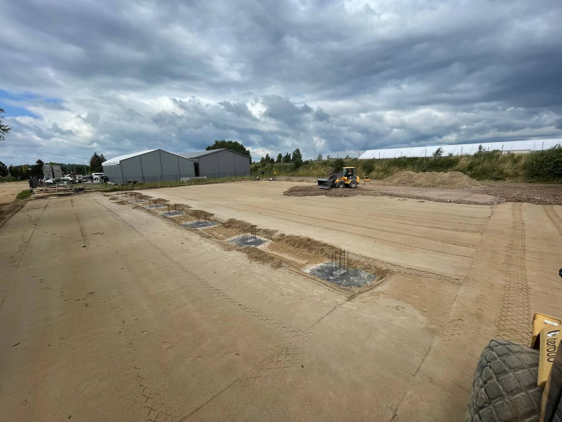 Plac budowy hali stalowej z kotwami i ciężkim sprzętem budowlanym